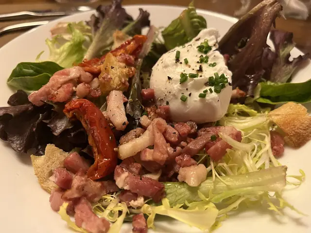 Salade lyonnaise : lardons, croûtons et œuf poché sur un lit de frisée