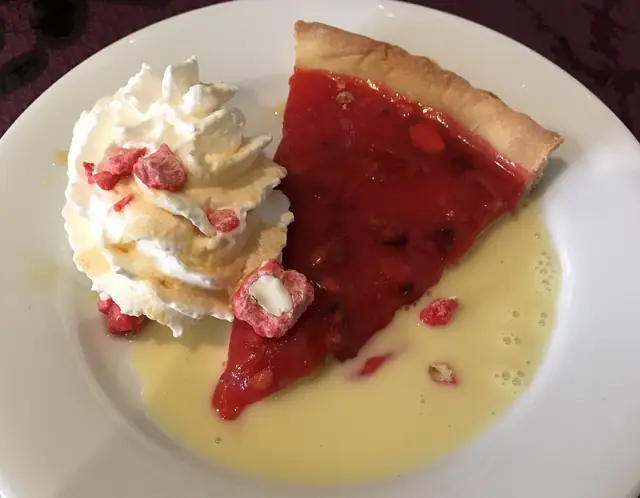 Une part de tarte aux pralines roses, crème anglaise et chantilly